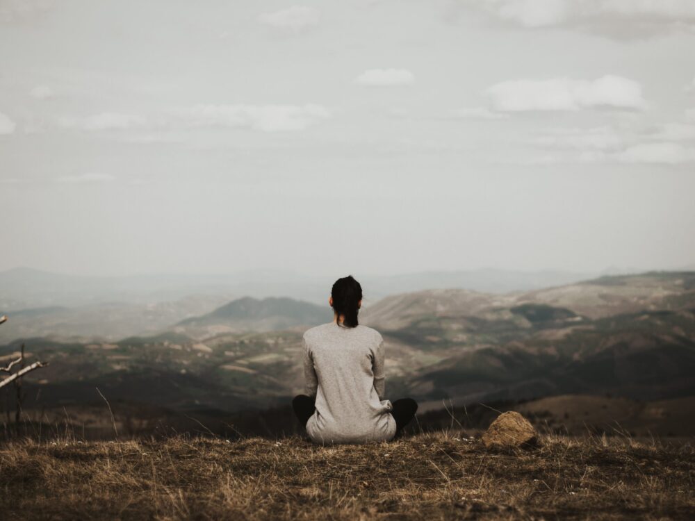 Person sits on mountain and meditates