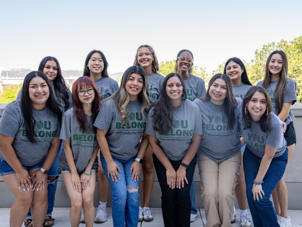 A group of CSU Human Development and Family Studies peer mentors smile at CSU's Behavioral Sciences Building