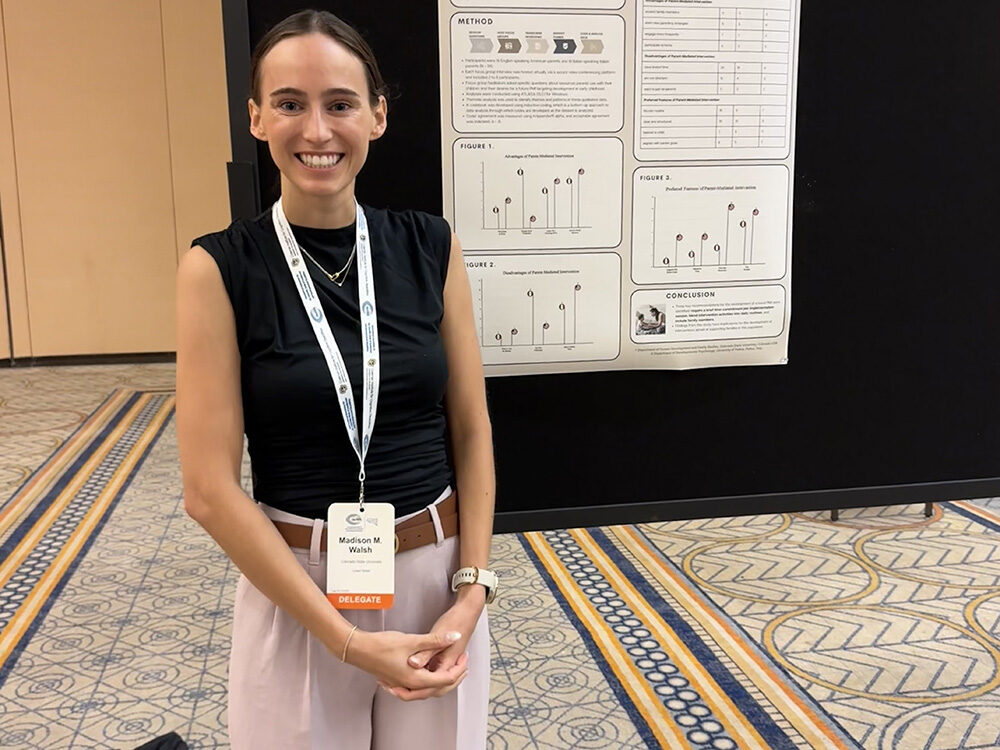 Madison posing in front of research poster at IASSIDD Conference