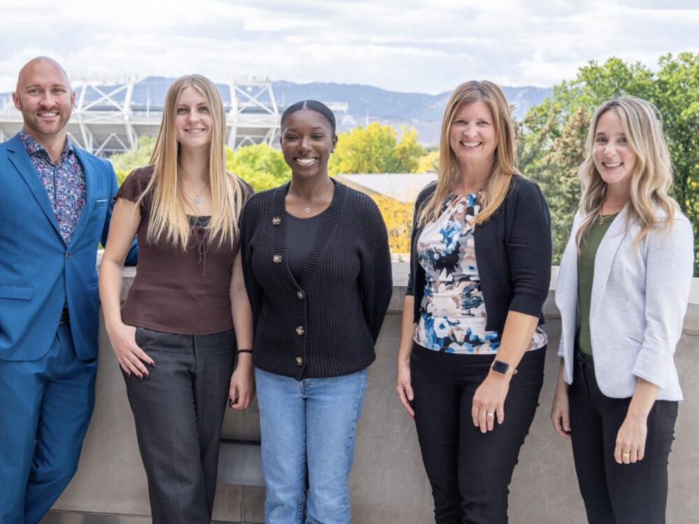Jenn Finders and the PEACE Lab team, a group of five, smile while outdoors.