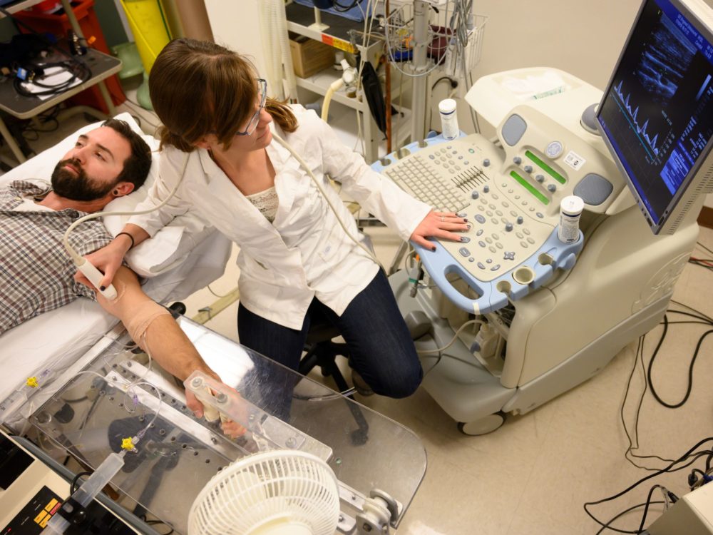 Researcher looks at the monitor as she performs an ultrasound on the patients arm