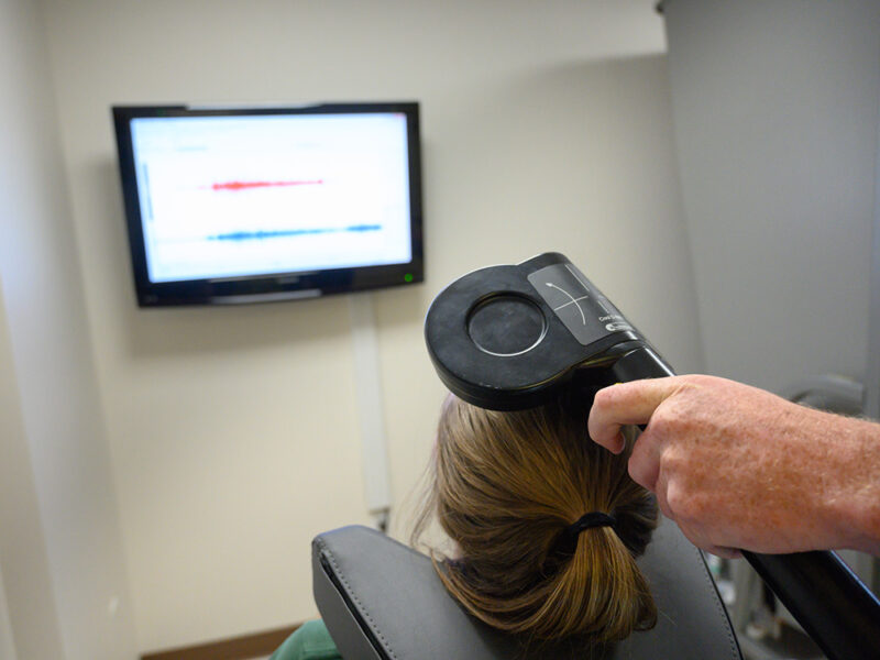Lab member performs transcranial magnetic stimulation and a participant. This technology can be used to indirectly assess neurotransmitter function within the brain. Through non-invasive brain stimulation we can determine both the brain’s excitability and its inhibitory capacity.