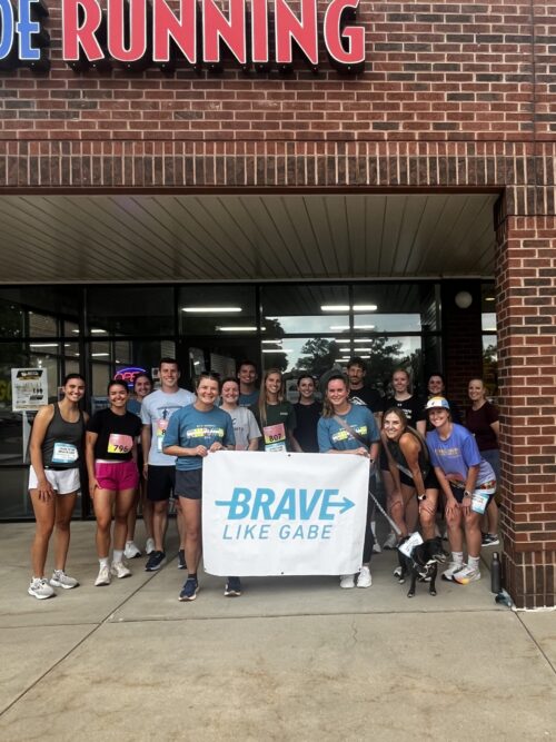 A large group of PATP Lab members and community members smile outside of a running store.