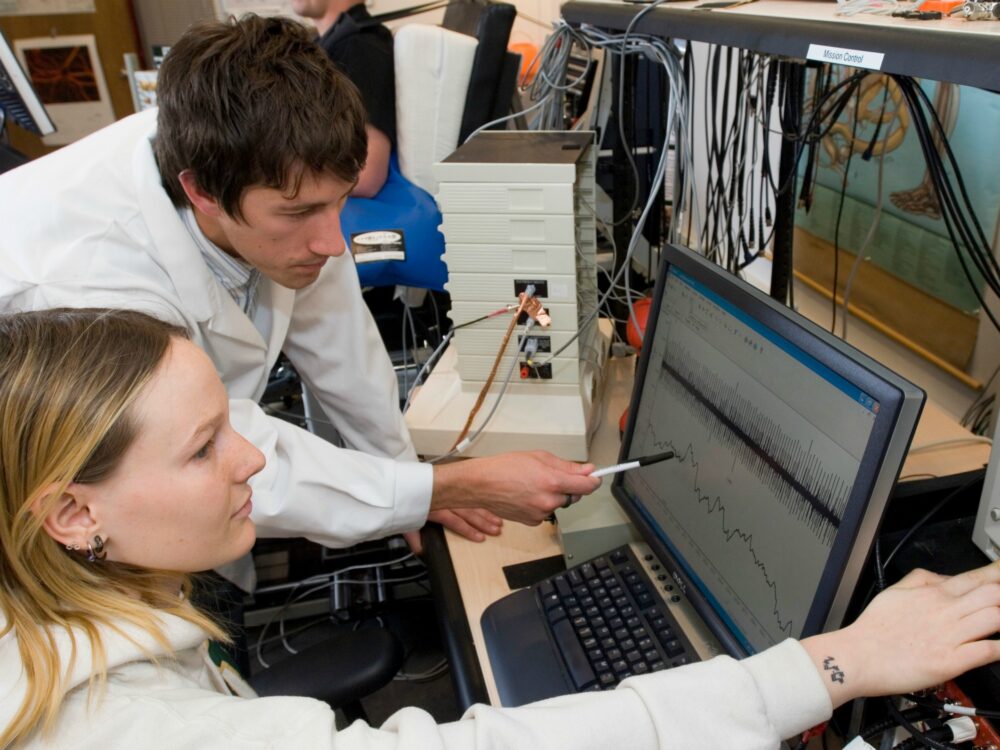 A researcher and student look at computer screen together