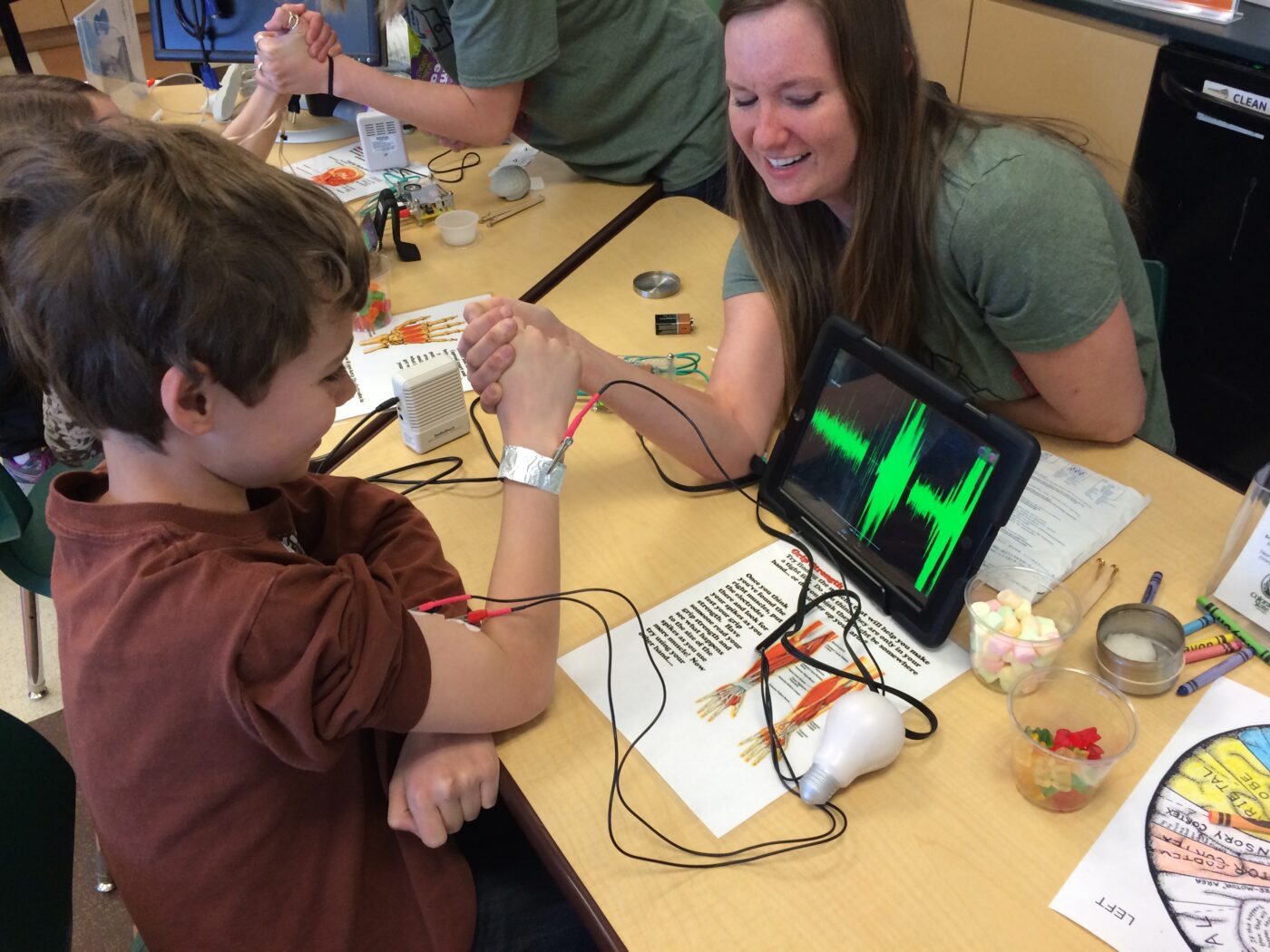 A Muscles Alive student talks to a some kids with the equipment