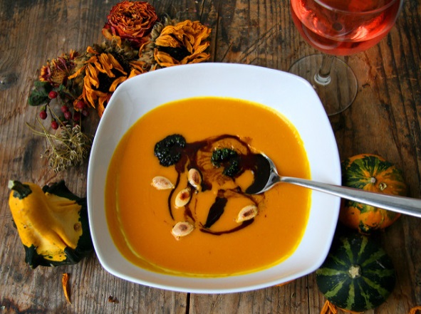 Pumpkin and black bean soup in bowl next to decorative gourds and flowers