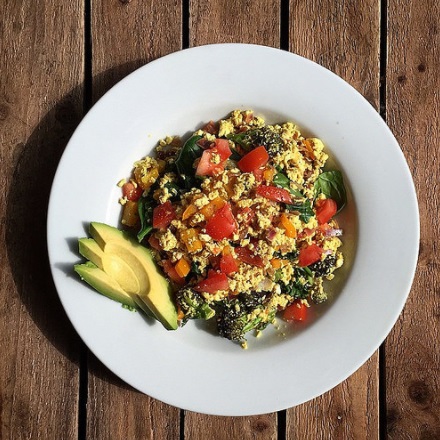 Herb tofu scrambled eggs with vegetables and sliced avocado