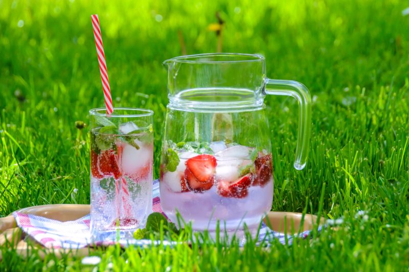 water pitcher with strawberries sitting in grass