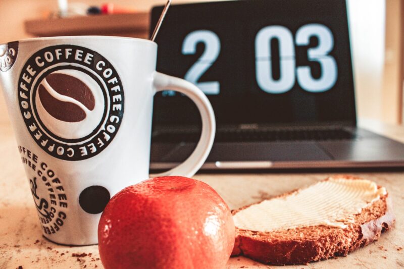 Clock, coffee mug, toast with spread, orange