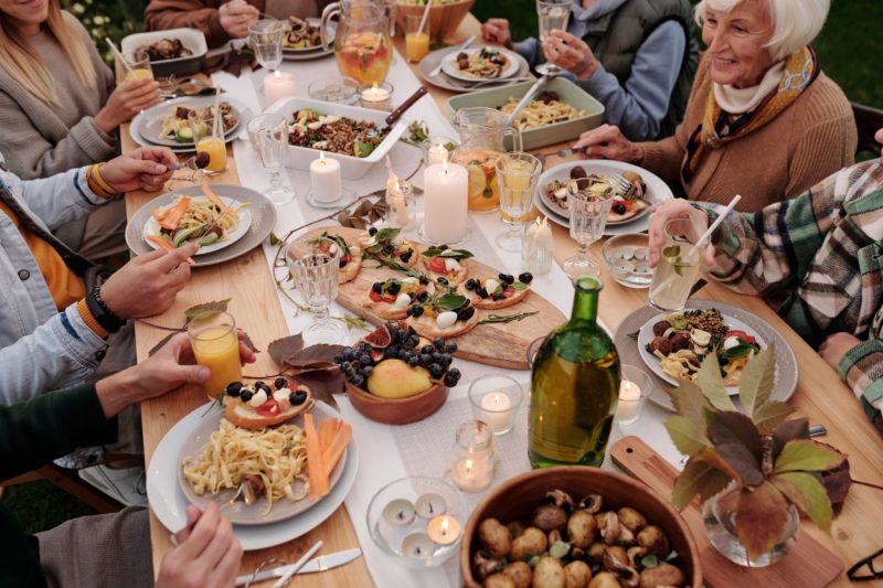 people sitting at a table with plates of food, drinks and candles
