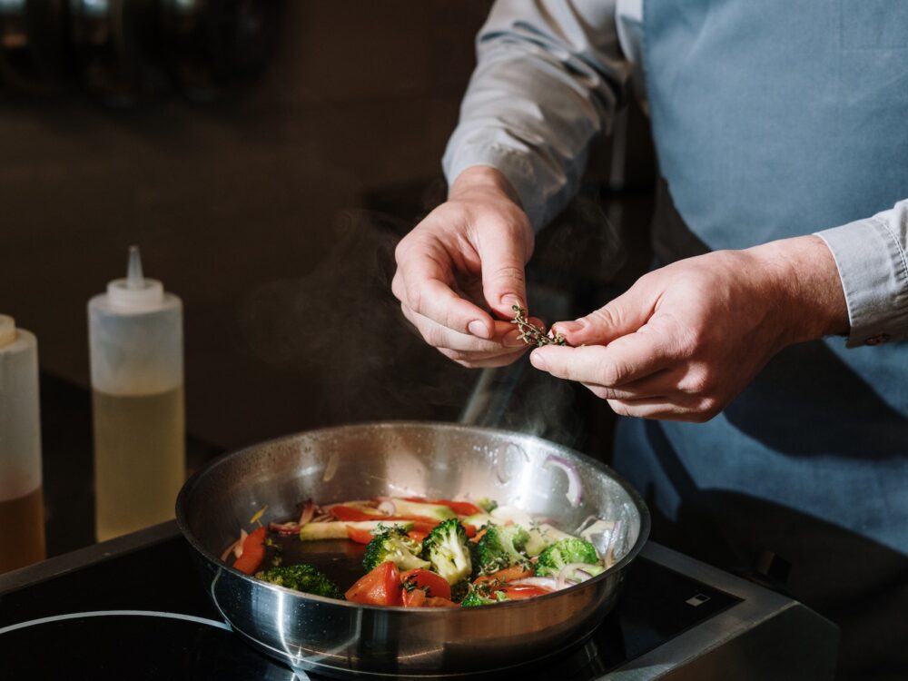 person cooking vegetables in a skillet