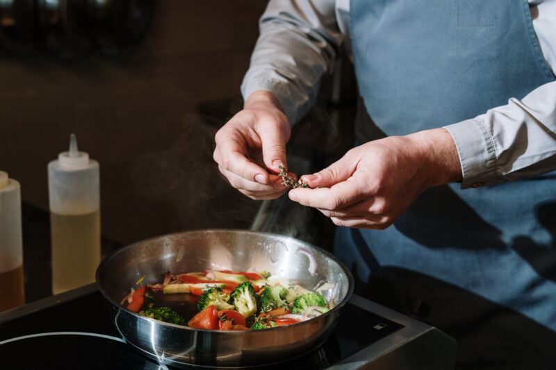 person cooking vegetables in a skillet