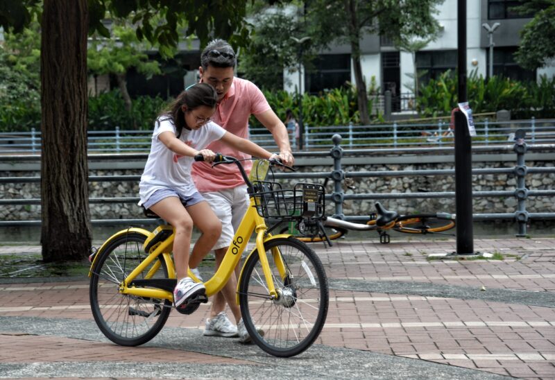 girl riding bike next to man