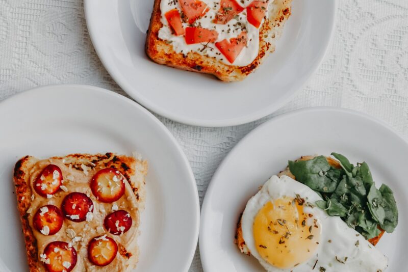 three types of toast with toppings such as tomatoes and cheese, egg and greens