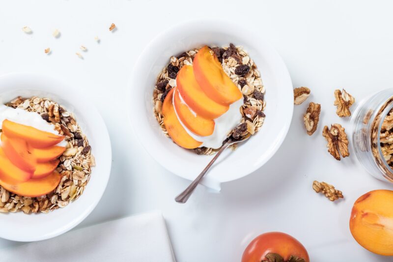 yogurt and granola in bowl with peach slices and raisins