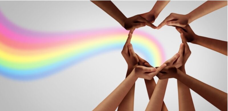 hands forming a heart shape, with a rainbow in the background