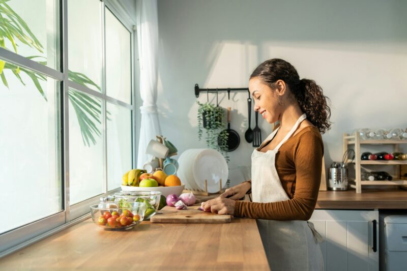 Woman chopping vegetables in front of window