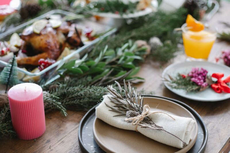 table set for a holiday meal with plates, napkins, greenery and candles
