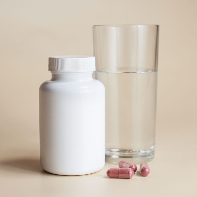 glass of water with a bottle of vitamins nearby