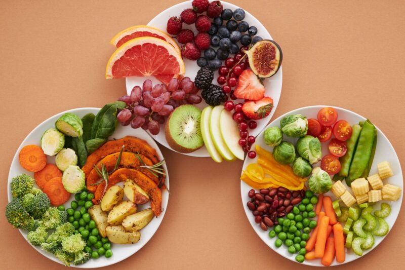 three white plates filled with fresh fruits and vegetables