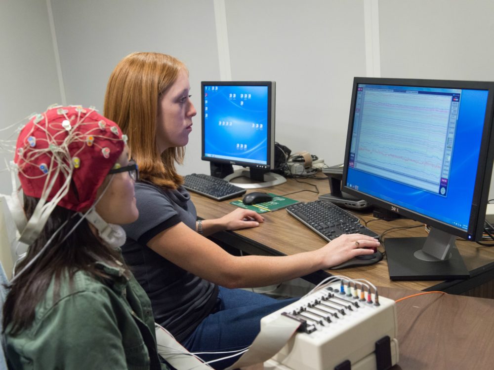 A student and subject looking at brainwaves on the computer.