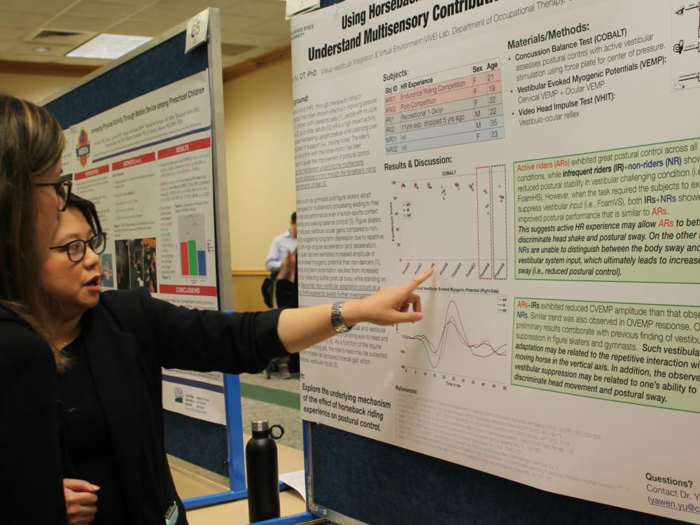 Yawen Yu explaining her research poster to a visitor