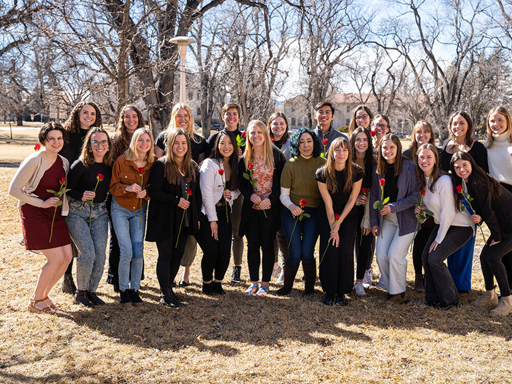 A large group of students holding roses after being initiated into a club