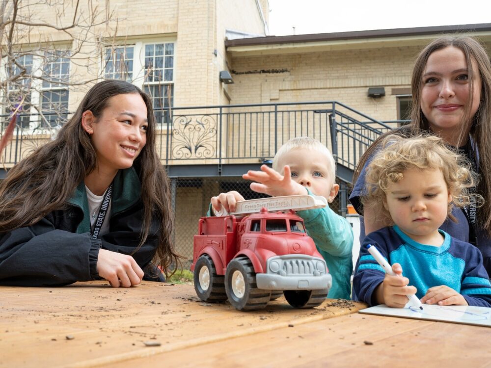 CSU students smile and interact with young children at the Early Childhood Center