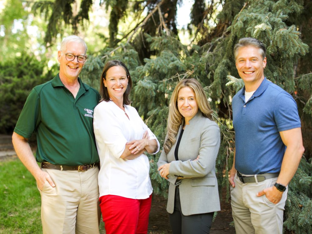Dave MacPhee, Christine Fruhauff, Debbie Fidler, Nate Riggs stand and smile outside in summer