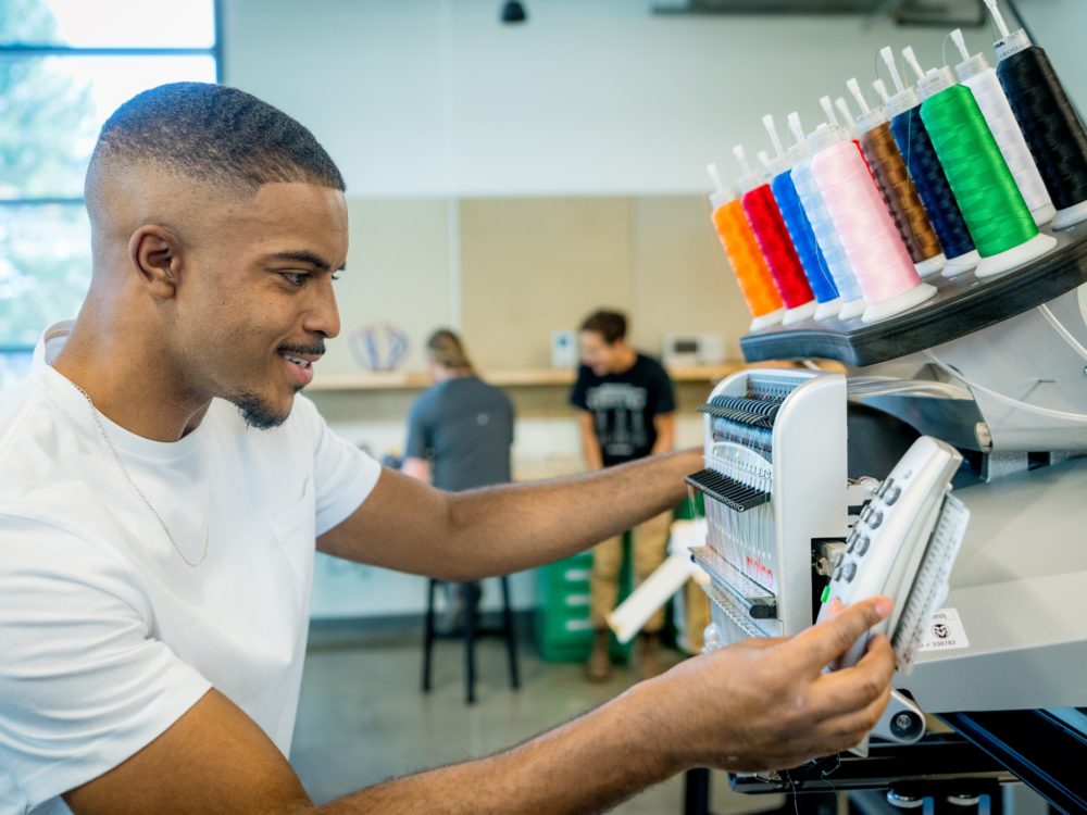 A student using the embroidery machine in the Prototyping Lab