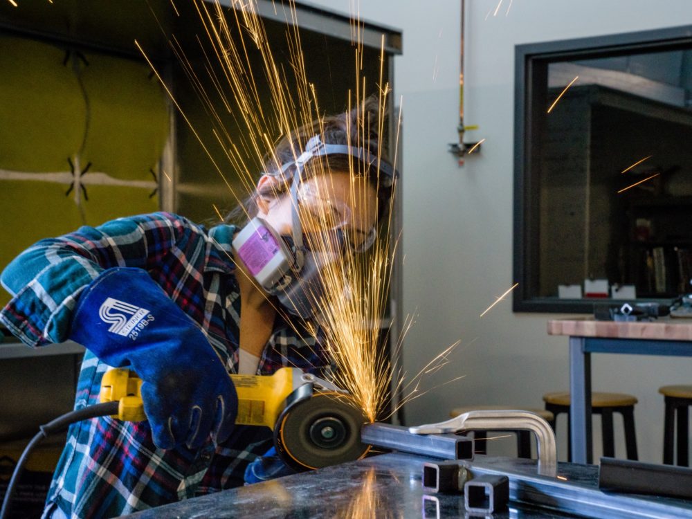 A student using the angle grinder in the Metal Lab