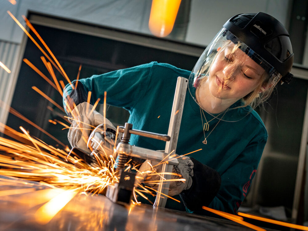 A close-up view of a student using an angle grinder in the Metals Lab