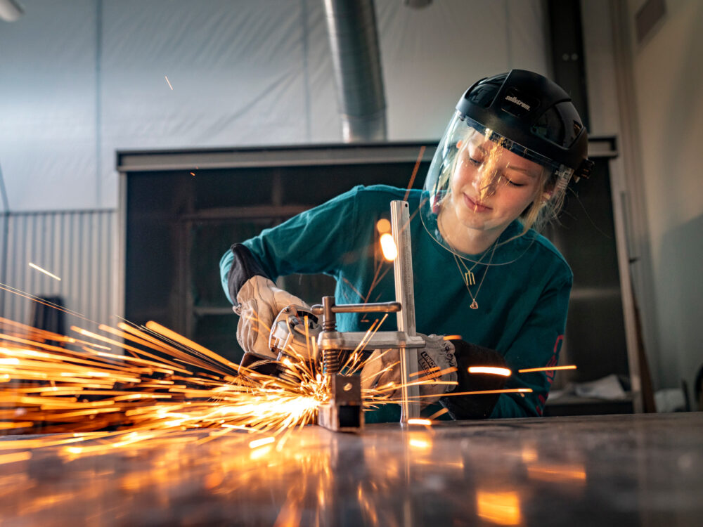 A student uses an angle grinder in the Metals Lab as sparks fly