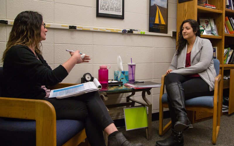Two students, both presenting as female, practice counseling skills while sitting across from each other
