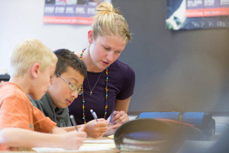 Student teacher works with two students in middle school classroom