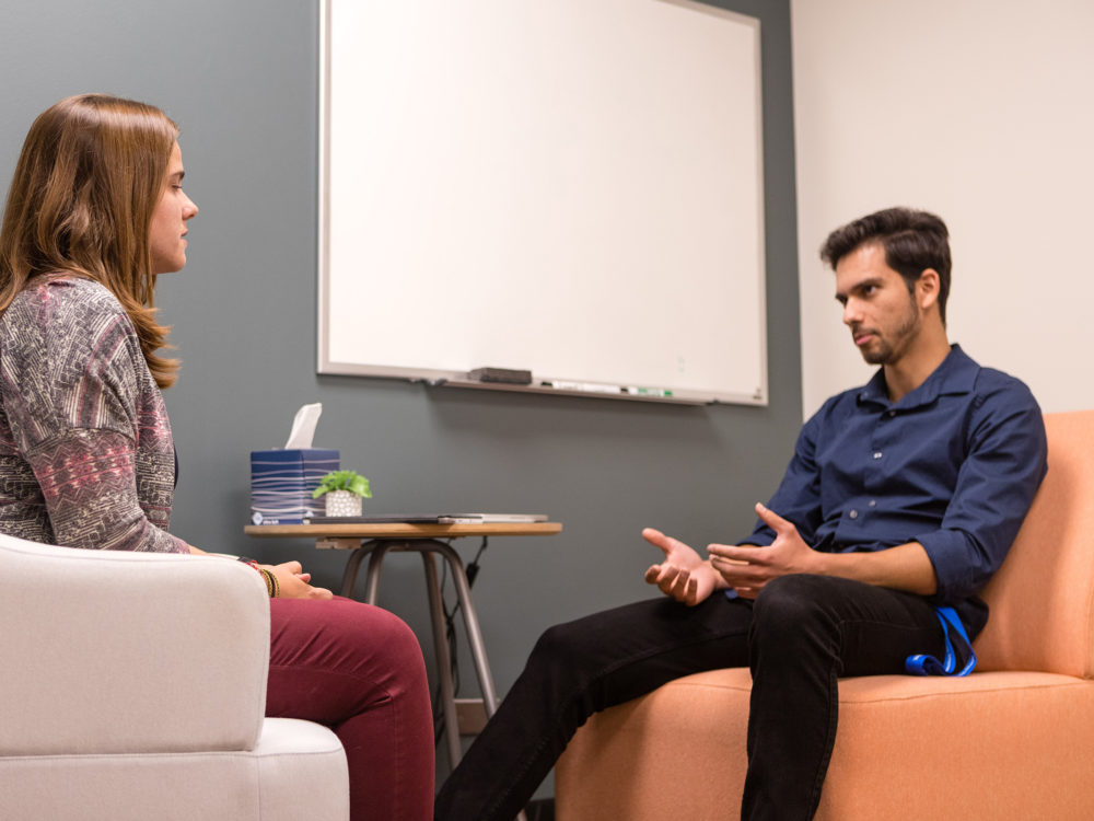 Student-counselor and peer sit across from each other in practice clinic