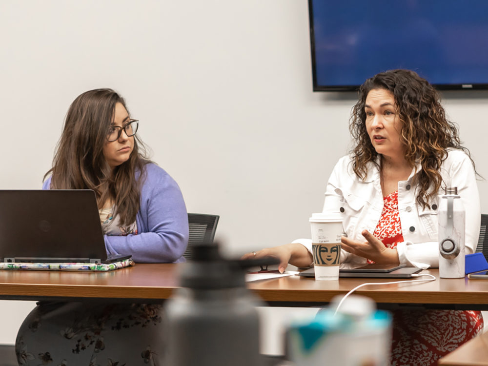 Dr. Susana Munoz, right, lectures during a Higher Education Leadership class while a student who presents as female, left, listens attentively