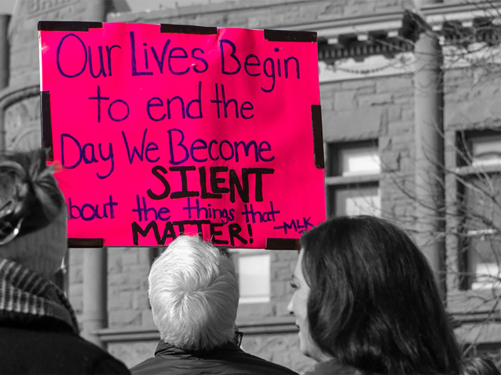 Protesters hold a sign that reads, `Our lives begin to end the day we become silent about the things that matter -MLK`