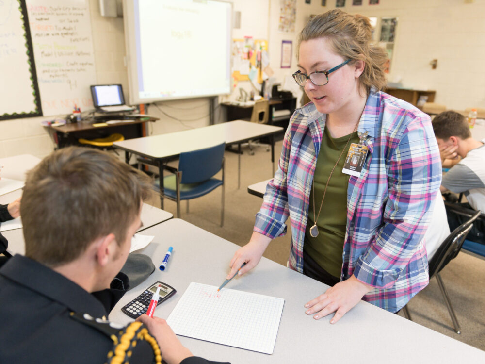 A student teacher helps high school student with an assignment