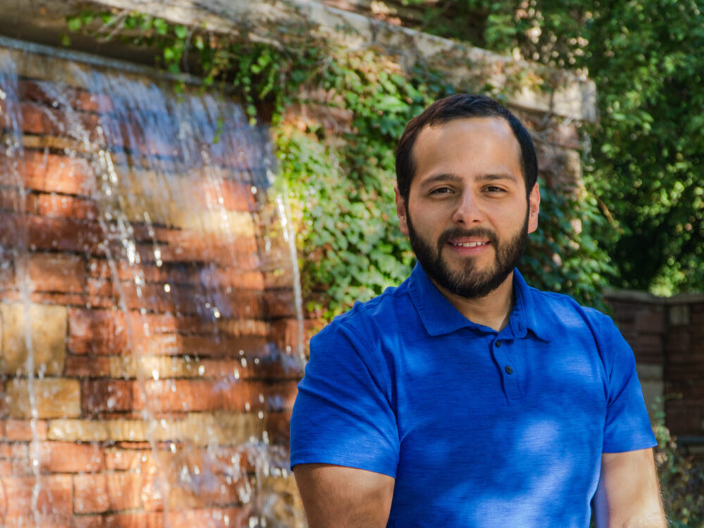 Arnold Cantu poses in front of the Education building waterfall.