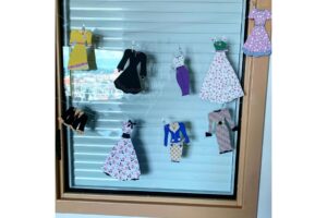 A photo of an office door with cut outs of dresses.