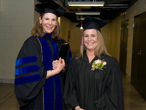 April Mason in commencement regalia with a student prior to commencement ceremonies.