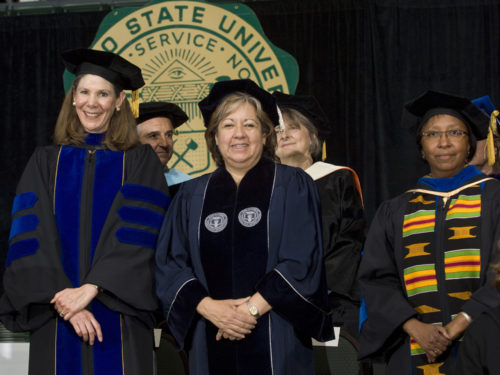 April Mason and a group of her colleagues wear commencement regalia and smile during CSU commencement ceremonies.