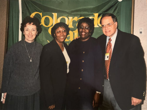 Cheryl Presley smiles in front of a Colorado State University banner with colleagues.