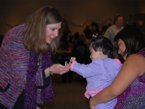 April Mason engages with a baby and her mother at a community event.
