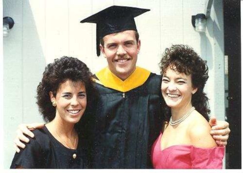 Kelly with two colleagues, one wearing a cap and gown