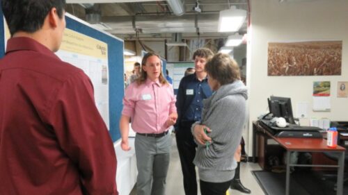 Mary talking with three students at a poster show
