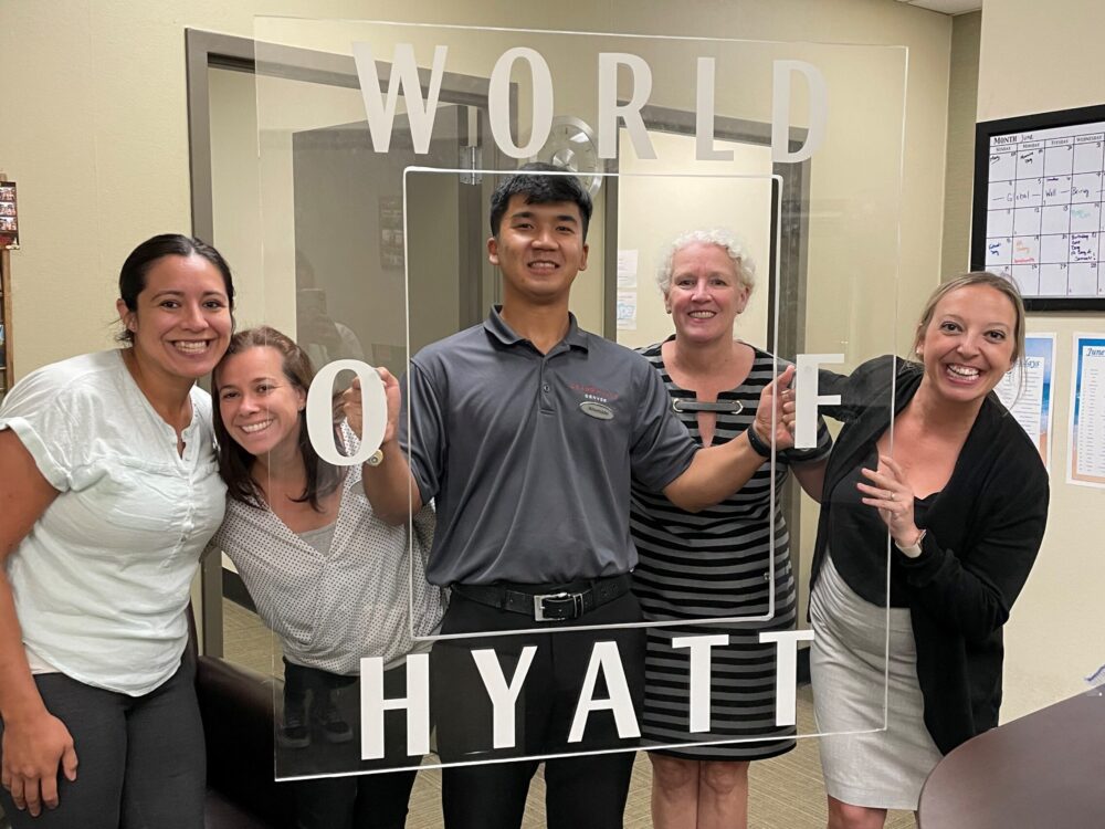 Interns pose with a clear acrylic frame etched with World of Hyatt