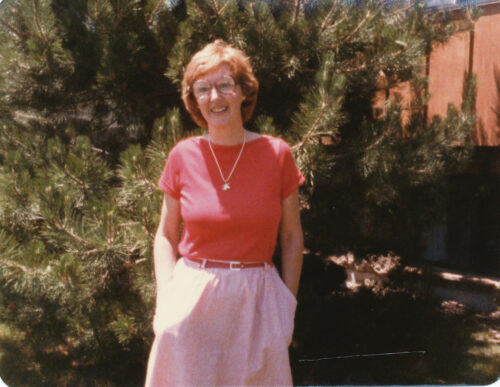 An outdoor portrait of a younger Janet Fritz wearing an orange shirt