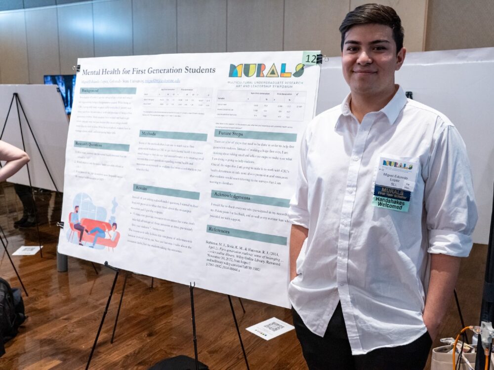 A student standing in front of a research poster